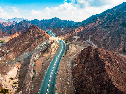 Desert road through Hajar mountain range stretching through United Arab Emirates and Oman aerial view