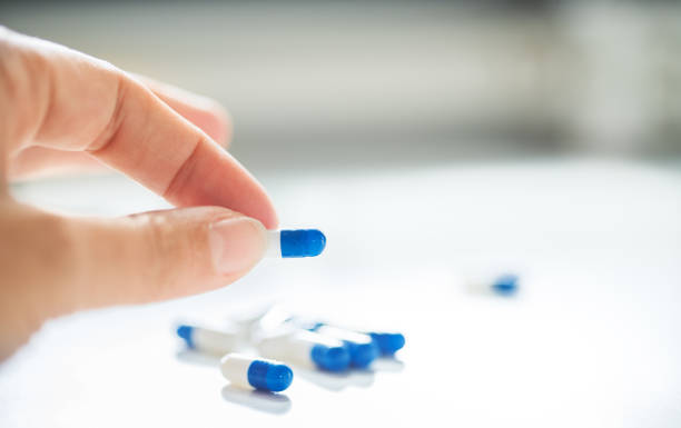 Take one every morning Close-up of a female hand holding a white and blue capsule morning after pill stock pictures, royalty-free photos & images