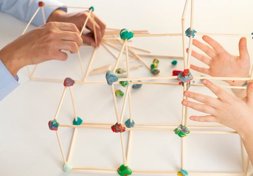 Father and daughter building construction with cubes made of craft sticks and play dough.