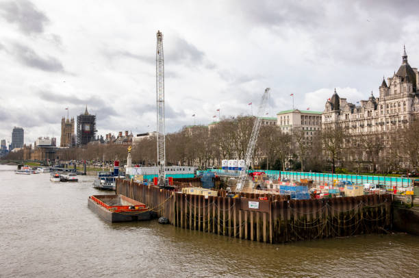 Construction of part of the Thames Tideway ‘super-sewer’ which is being built for 16 miles (25km) beneath the River Thames in London in order to catch, store and convey any sewage and rainwater which currently pollutes the river on occasions. It is due to be completed in 2024 and will run from Acton in West London to Abbey Mills in East London. This section is beside the Victoria Embankment near the Palace of Westminster. (Incidental people.)