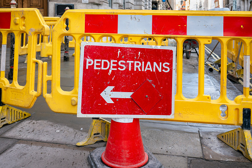 Repairs have been done to part of the pavement in Fleet Street, City of London, and the workmen have left barriers and signs behind to stop pedestrians walking on the wet cement.