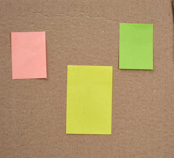 istock blank pink, yellow and green papers glued on a brown cardboard surface 1227354952