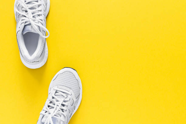 istock White sneakers isolated on a yellow background 1227355599