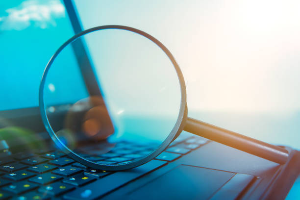Laptop computer with magnifying glass stock photo