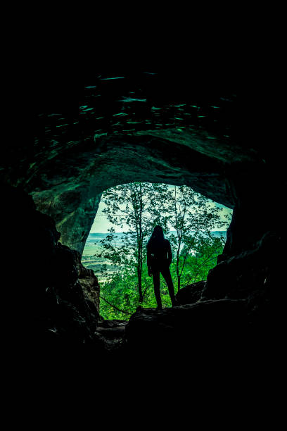 istock Female silhouette in a cave in the woods 1227357145