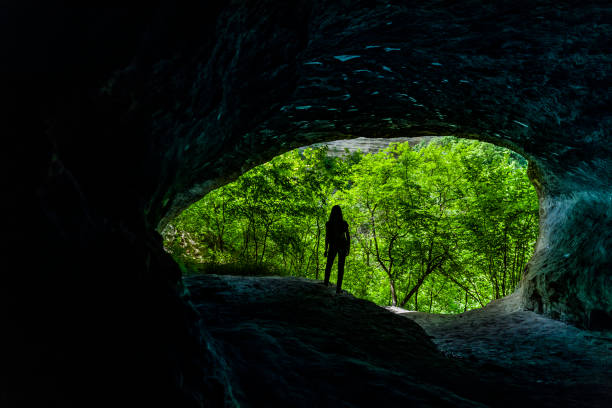 istock Female silhouette in a cave in the woods 1227357197