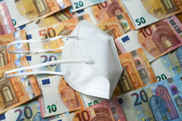 white protective medical face mask laying on the european union money currency euro - european union euro note european union currency paper currency currency imagens e fotografias de stock
