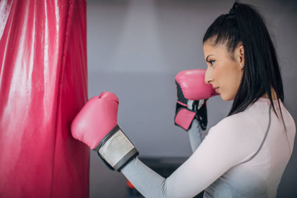 istock Lady boxer punching the punching bag in gym 1227360721
