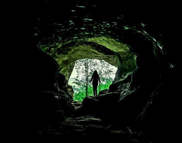 istock Female silhouette in a cave in the woods 1227360876