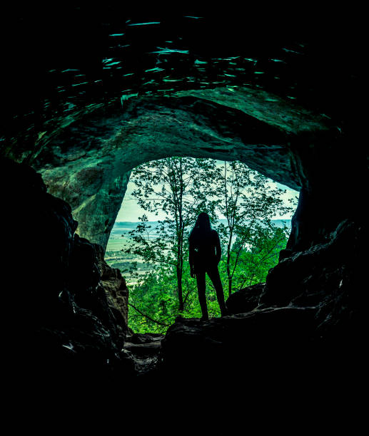 istock Female silhouette in a cave in the woods 1227360885