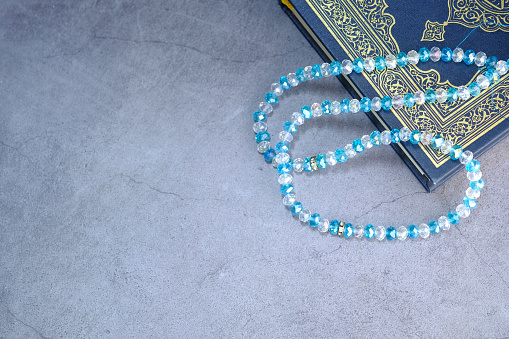 Koran, prayer beads on the pink background