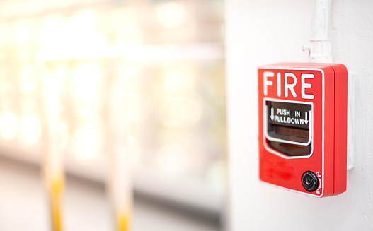 The red fire alarm switch on the white wall at the supermarket, for the safety first when the fire being.