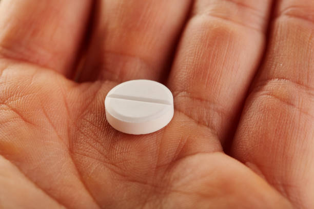 istock White round medical pill in the palm 1227367257