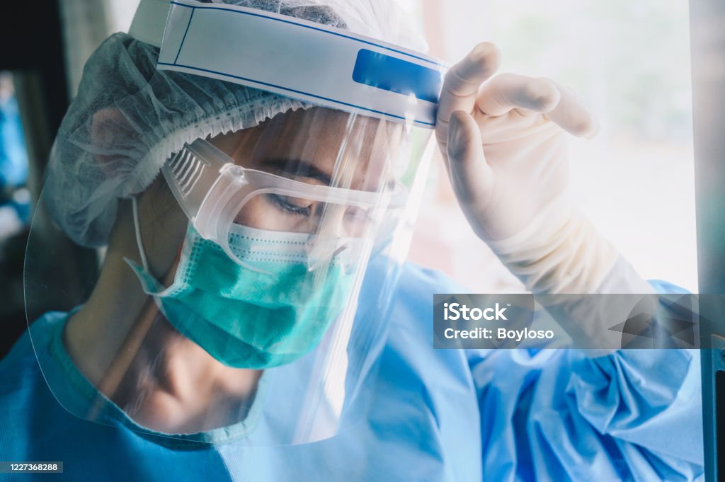 Nurse having headache and tired from work while wearing PPE suit for protect coronavirus disease. The wellbeing and emotional resilience are key components of maintaining essential care services. Coronavirus Stock Photo