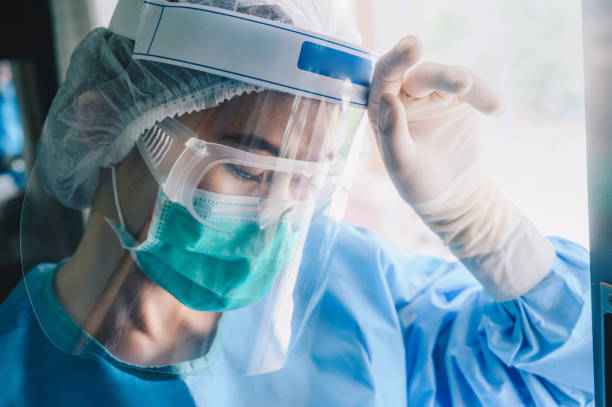 Nurse having headache and tired from work while wearing PPE suit for protect coronavirus disease. The wellbeing and emotional resilience are key components of maintaining essential care services. protective glove photos stock pictures, royalty-free photos & images