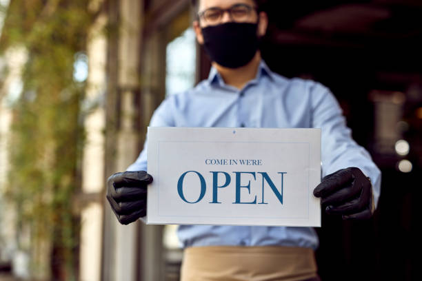 istock Close-up of waiter holding open sign. 1227368712