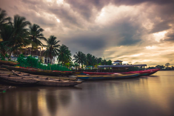 Boats parked at the banks of the Wouri river Shot from Bonassama using the long exposure technique at sunset, this picture depicts a colourful view of the banks of the Wouri river. The tropical vibe reflects the beauty of Cameroon wouri river stock pictures, royalty-free photos & images