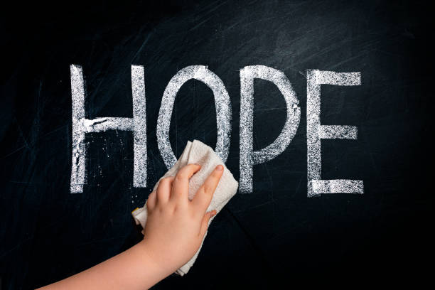 istock Social issue metaphor - Hand wiping off chalk word HOPE on chalkboard using rag 1227372199