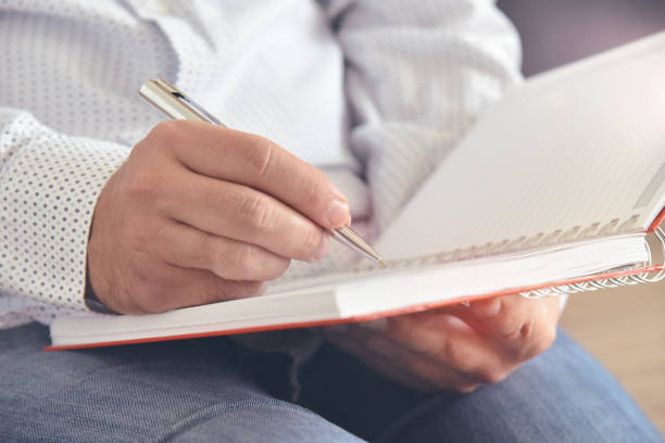 istock Close-up of man’s hands holding and writing in a notebook. 1227380206