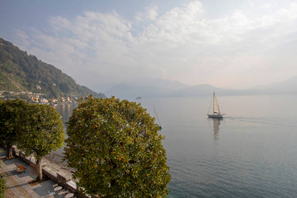 la barca a vela lontana galleggia in acque calme del lago maggiore - 11207 foto e immagini stock