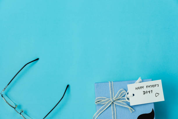 Table top view Happy Fathers day holiday background concept.Flat lay  gift  box for dad with accessories objects sign of season the eyeglasses ,Gift box and greeting card on blue paper.copy space.