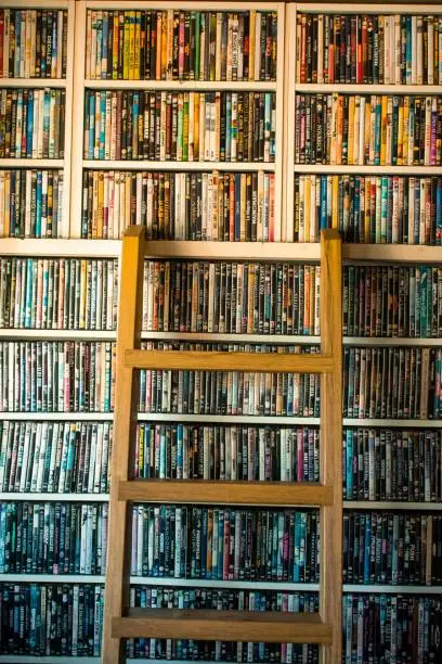 Movies in DVD cases on a shelf and a ladder used as decoration for a pub