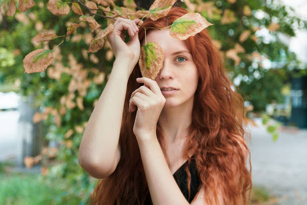 Ginger girl with long hairs in autumnal park.