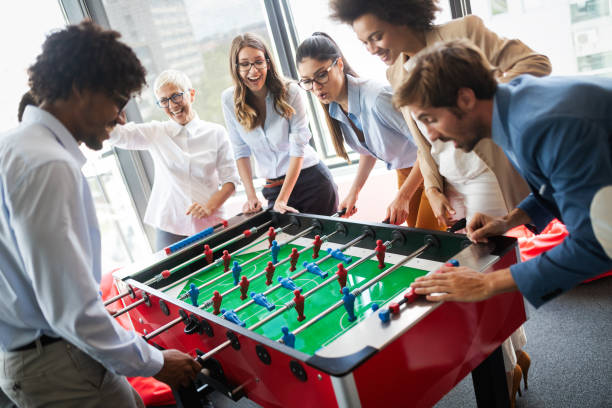 Employees playing table soccer indoor game in the office during break time