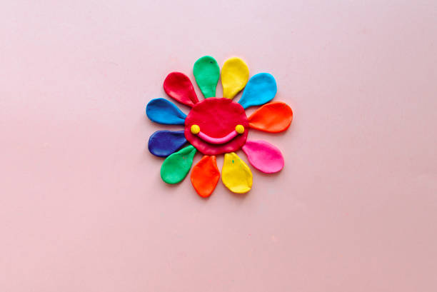 cute flower made of multi-colored plasticine clay on a pink background, multi-colored dough, minimal, children's crafts