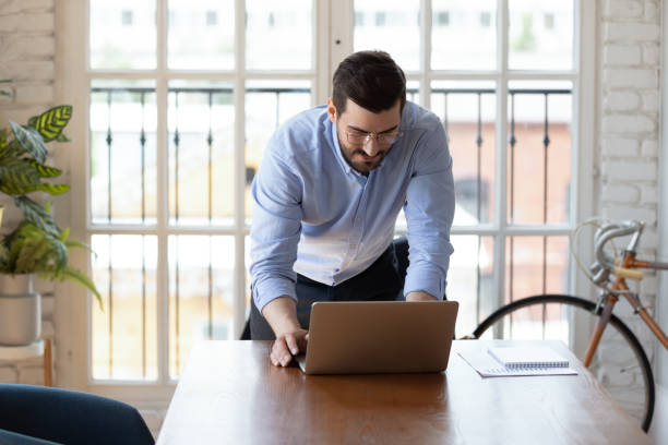 istock Confident businessman wearing glasses using laptop in modern office 1227397571