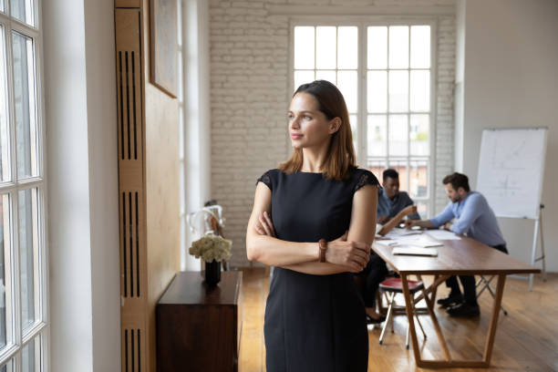 istock Confident businesswoman standing in office, looking through window 1227397626