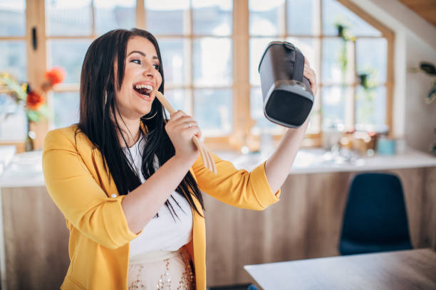 istock Woman singing and dancing at home and holding wireless bluetooth speaker 1227397987