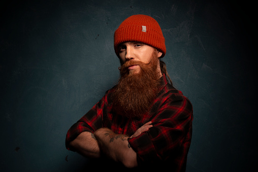 Red bearded man with orange hat and plaid shirt on the cyan background