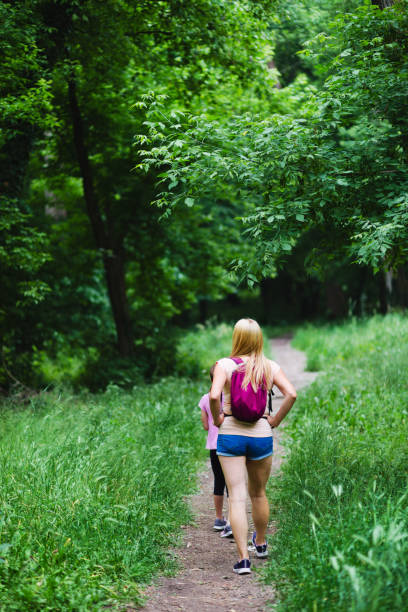 Young woman and her daughter are walking outdoors in the woods.
