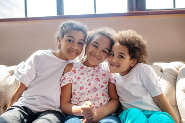istock Three curly-haired kids sitting on the sofa and smiling 1227404434