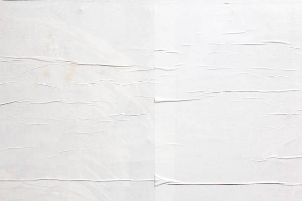 istock White crumpled wavy paper poster glued on billboard texture background. Copy space for text. 1227404881