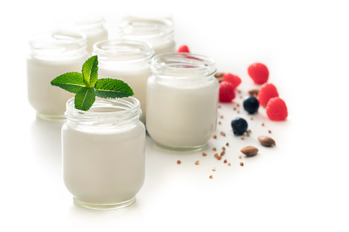 Homemade yoghurt yogurt in glass pots with mint leaves berries granola isolated on white background