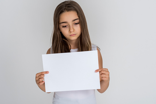 Cute teenage girl holding a white empty placard (for you to copy space) over white background