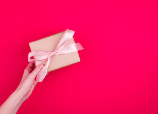 istock A beautiful gift box with satin ribbon in hand. 1227409347