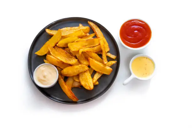 French fries homemade isolated on white with sauces ketchup mustard and mayonnaise on black dish plate