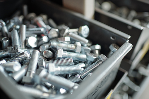 Close-up of silver screws placed in metal box, repairman or furniture maker workplace concept