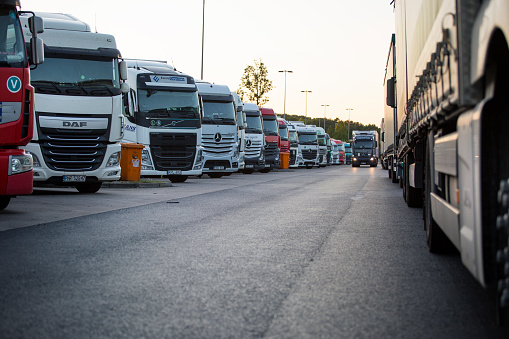 Medenbach, Germany - May 25, 2020: Parked trucks on German rest area Medenbach and passing vehicles on highway A3 in Germany at dusk. Many rest areas are completely overloaded during evening hours due to the high truck traffic density in Germany