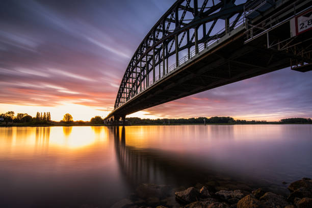 Striking arch bridge spans the river during the sunrise Old 'IJssel brug' near the city of Zwolle in Overijssel, the Netherlands, Architectural feature at sunset ijssel photos stock pictures, royalty-free photos & images