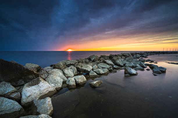 Breakwater of large rocks in the Ijsselmeer near the town of Urk in the province of Flevoland during a dramatic sunset with great clouds and colours