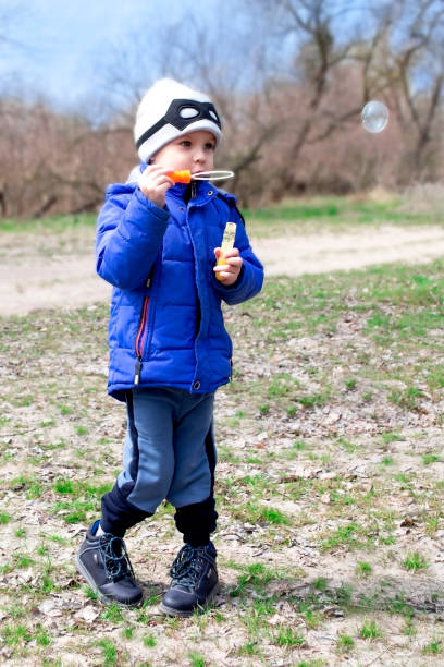 istock Boy blowing soap bubbles in nature 1227421736