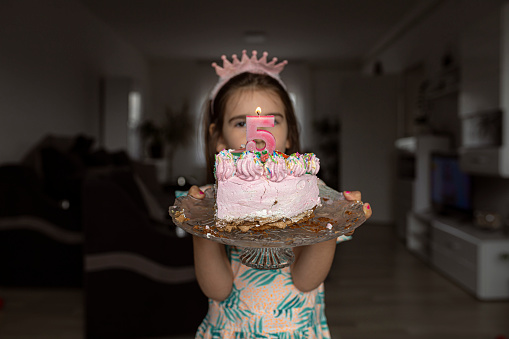 Young girl holding a cake with number five on it