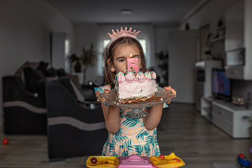 Young girl holding a cake with number five on it