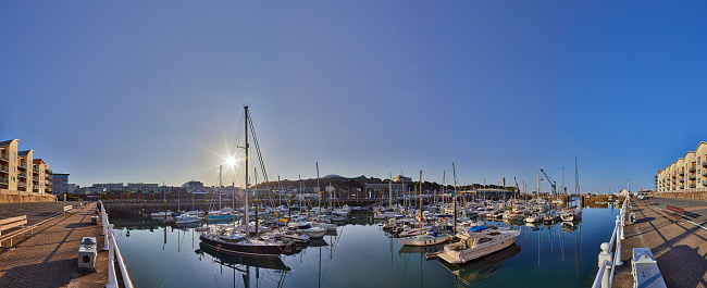 Panoramic image of St Helier Marina early morning from the West marina wall with the visitor births on the left hand side and the entrance on the right hand side of the image. Jersey, Channel Islands, UK