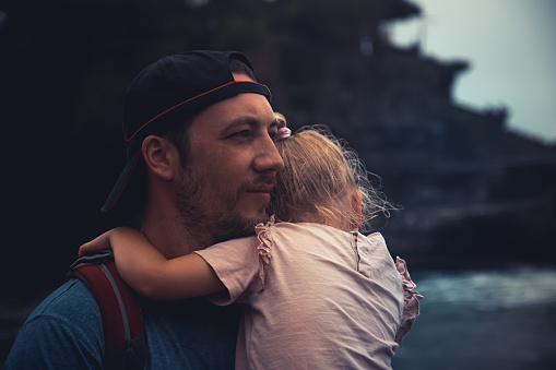 Pensive lonely man father holding his child daughter looking with hope into distance in dark vintage style