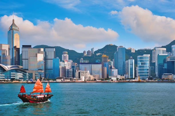 Junk boat in Hong Kong Victoria Harbour Hong Kong skyline cityscape downtown skyscrapers over Victoria Harbour in the evening with junk tourist ferry boat on sunset with dramatic sky. Hong Kong, China victoria harbour stock pictures, royalty-free photos & images